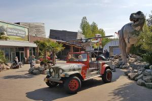 Kinderen spelen in een oude terreinwagen vlak naast een enorme dino en een prachtig oud vliegtuig dat omgeturnd is tot glijbaan