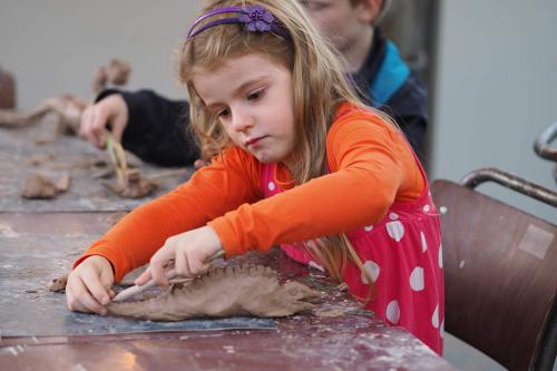 Meisje dat druk bezig is om een prachtige dino te kleien